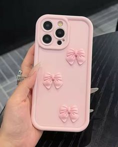 a person holding up a pink phone case that has bows on the front and sides