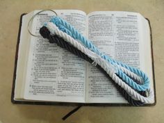 an open bible with blue, white and black rope wrapped around it