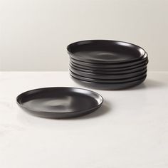 stack of black plates sitting on top of a white countertop next to each other