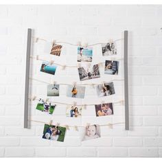 a white brick wall with pictures hanging on clothes pins and photos pinned to the pegs