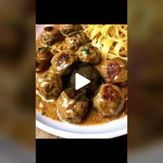 a white plate topped with meatballs covered in gravy next to pasta noodles