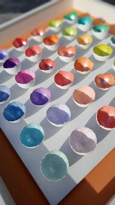 an array of different colored paper plates on a white surface with orange and brown edges