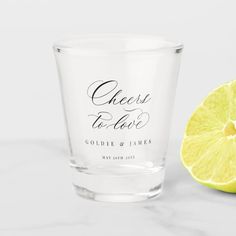 a shot glass next to a lemon on a white surface with the words cheese is love printed on it