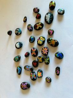 many different colored rocks are arranged on a white surface with black and blue flowers in the middle