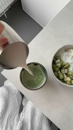 a person pouring yogurt into a bowl next to a bowl of broccoli