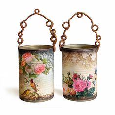 two tin canisters with flowers painted on them and chains hanging from the sides