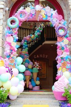 an entrance to a candy shop decorated in pastel colors with balloons and candies