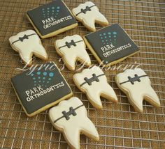 decorated cookies with black and white icing are arranged on a cooling rack for display