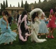 several women dressed up in costumes standing on the grass