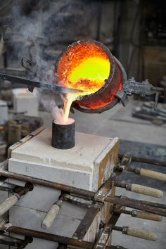 an iron melting in a pot on top of a block of wood and some metal