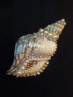 a brooch with pearls and beads on it's side, sitting on a black surface