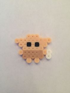 an animal made out of plastic beads on a white surface with one eye open and the other half closed