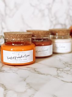 three jars of honey sit on a marble counter