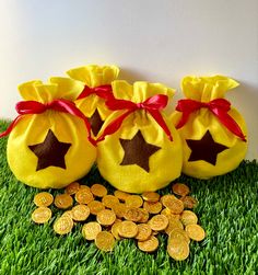 three bags filled with gold coins sitting on top of green grass next to each other