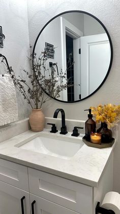 a bathroom sink with a mirror above it and flowers in vases on the counter