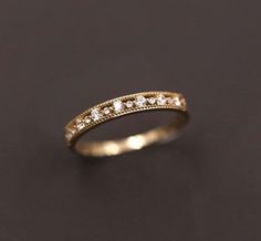 a gold wedding band with small diamonds on it's sides, sitting on a black surface