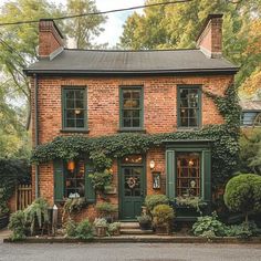 a brick house with green shutters and ivy growing on the front door, surrounded by greenery