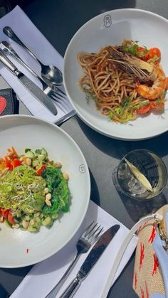 two white plates topped with different types of food next to silverware and utensils