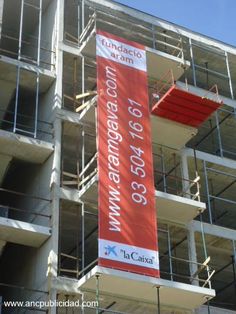 a large red banner hanging from the side of a building next to scaffolding