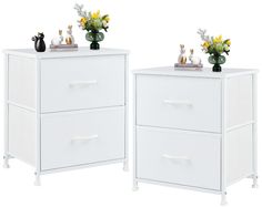 two white nightstands with flowers and vases on top of each drawer, both side by side