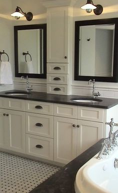 two sinks and mirrors in a bathroom with white cabinets, black counter tops and drawers