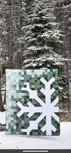 a quilted snowflake is displayed in the middle of a snowy forest with trees