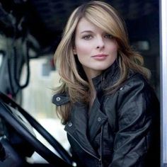 a woman sitting in the driver's seat of a truck wearing a black leather jacket