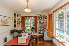 a home office with wood floors and lots of bookshelves on the windowsill