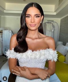 a woman in a white dress posing for the camera with her hands on her chest