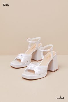 We recommend styling the Lulus Remie White Satin Knotted Platform High Heel Sandals with any look that needs an extra dash of fabulousness! Sleek woven satin shapes these iconic heels that feature a trendy square footbed (atop a 0.75"" toe platform) and gather straps that create a wide, knotted peep-toe upper. A matching quarter strap secures around ankle with a gold buckle, all atop a chunky block heel. 3. 5" wrapped block heel. Lightly cushioned insole. Felted rubber sole has nonskid markings. Man Made Materials. Imported. Lulus | Remie White Satin Knotted Platform High Heel Sandal Heels. Ivory Block Heels, Iconic Heels, Low Chunky Heels, White Platform Sandals, Satin Heels, Sandal Heels, Chunky Block Heels, Platform High Heels, White Sandals