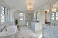 a large white bathroom with two sinks and a bathtub in the middle of it