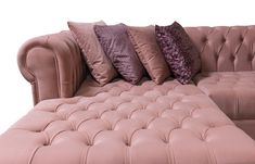 a pink leather couch with several pillows on it's back and one in the middle