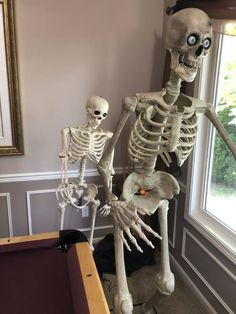 a skeleton playing pool in a living room