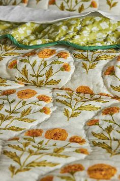 an unmade bed with yellow flowers and green leaves on the comforter is shown