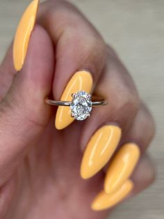 a woman's hand holding a yellow manicure with a diamond ring