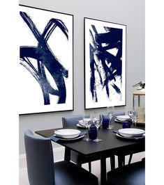 a dining room table with blue chairs and artwork on the wall