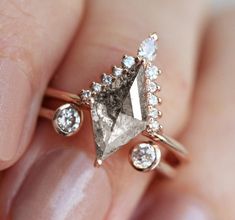 a woman's hand holding an engagement ring with a gray diamond in the middle