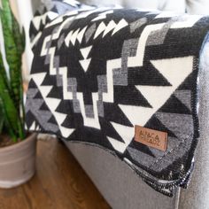 a black and white pillow sitting on top of a couch next to a potted plant