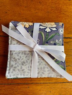 a cloth covered with white ribbon sitting on top of a wooden floor next to a piece of fabric