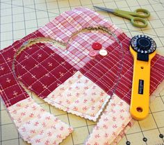 a pair of scissors sitting on top of a piece of fabric next to some sewing supplies