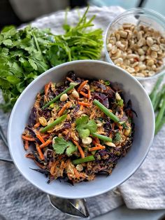 a white bowl filled with food next to another bowl full of vegetables and nuts on top of a table