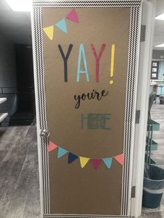 a door with the words yay you're here painted on it and bunting