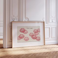 a white frame sitting on top of a wooden floor next to a wall with pink lipstick prints