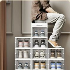 a man sitting on top of a white shelf filled with lots of pairs of shoes