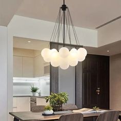 a dining room table with four chairs and a light fixture hanging from it's ceiling