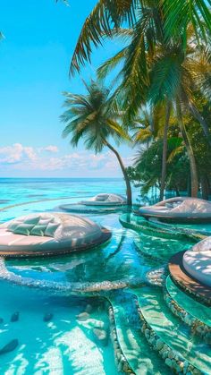 an outdoor swimming pool with lounge chairs and palm trees in the background, surrounded by clear blue water