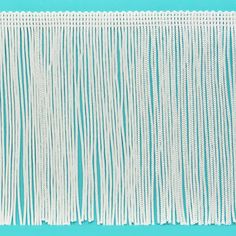 the side of a piece of white fabric with fringes on it, against a blue background