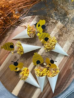 several cones filled with popcorn on top of a wooden table next to dried flowers and leaves