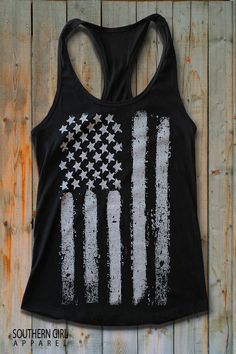 "White American Flag on black racerback Tank Top -These tanks are soft and comfortable, perfect for the music festivals, 4th of July or anytime... -60% Combed Ring-Spun Cotton 40% Polyester -30 single for extreme softness -Pre-shrunk for reduced shrinkage -Finished edge Measurements are taken lying flat across seam to seam 1\" below arm hole for chest Available in Small thru XL SMALL: Length- 28\" - Chest Width- 16\" across seam to seam MEDIUM: Length- 28 1/2\" - Chest Width- 17\" across seam to Black Racerback Tank Top With Letter Print, Black Grunge Tank Top With Letter Print, Black Grunge Tank T-shirt, Black T-shirt With American Flag Print For Summer, Black Flag Print Top For Summer, Black Tops With Flag Print For Summer, Black Flag Print Top For Streetwear, Black Cotton Racerback Top, Casual Black Top With Flag Print