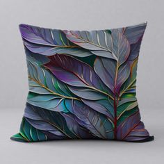 a decorative pillow with purple and green leaves on the front, against a gray background